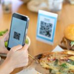 A person using a smartphone to scan a qr code on a pizza for review.